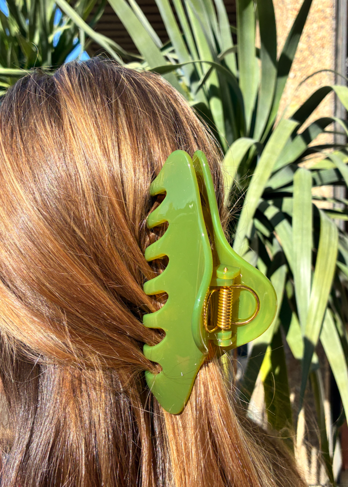 Green claw clip on a person's hair with a natural background