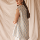 Woman wearing a light blue patterned set against a beige background