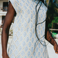 Person wearing a light blue patterned set with palm trees in the background