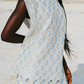 Person wearing a light blue patterned set on a beach.