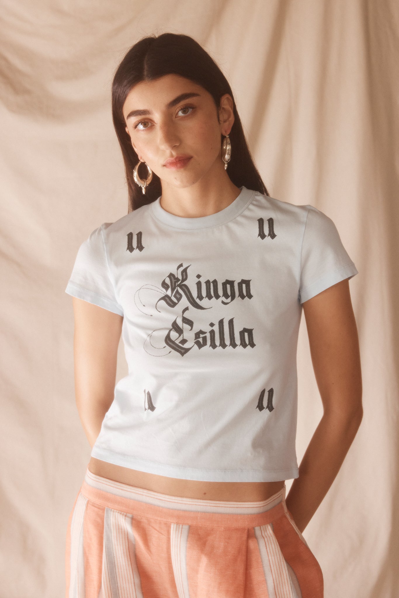 Woman wearing light blue cropped cotton tee with vintage gothic logo print, soft feel, and fitted silhouette