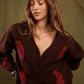 Woman wearing a brown coat with red accents against a green background