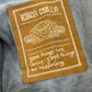 Brown patch with embroidered text and design on a gray fabric background