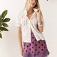 A woman modeling a white short-sleeve button-up shirt and a purple mini skirt with dark brown polka dots, standing against a white wall with green leaves in the corners.