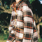 Woman wearing a plaid coat outdoors with trees in the background