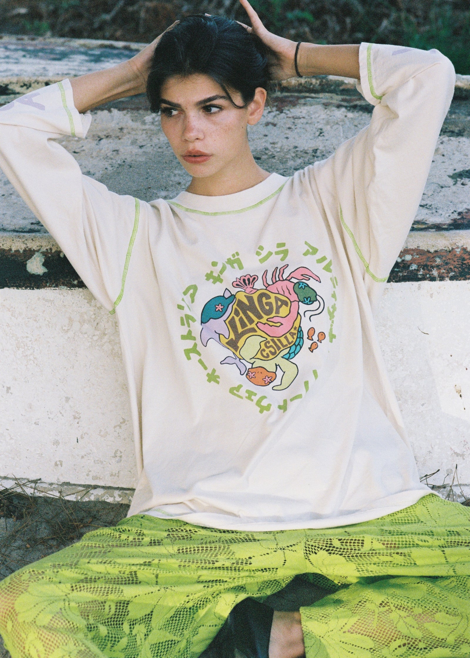 Person wearing a white t-shirt with colorful graphic design sitting on a wooden bench.
