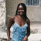 Woman wearing sheer blue sun embroidered slip with lace-trim neckline, spaghetti straps, and ethereal midi silhouette.