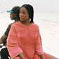 Woman in a red t-shirt dress sitting on a bike with a white background