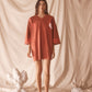 Woman wearing a red t-shirt dress with a heart design against a textured beige background
