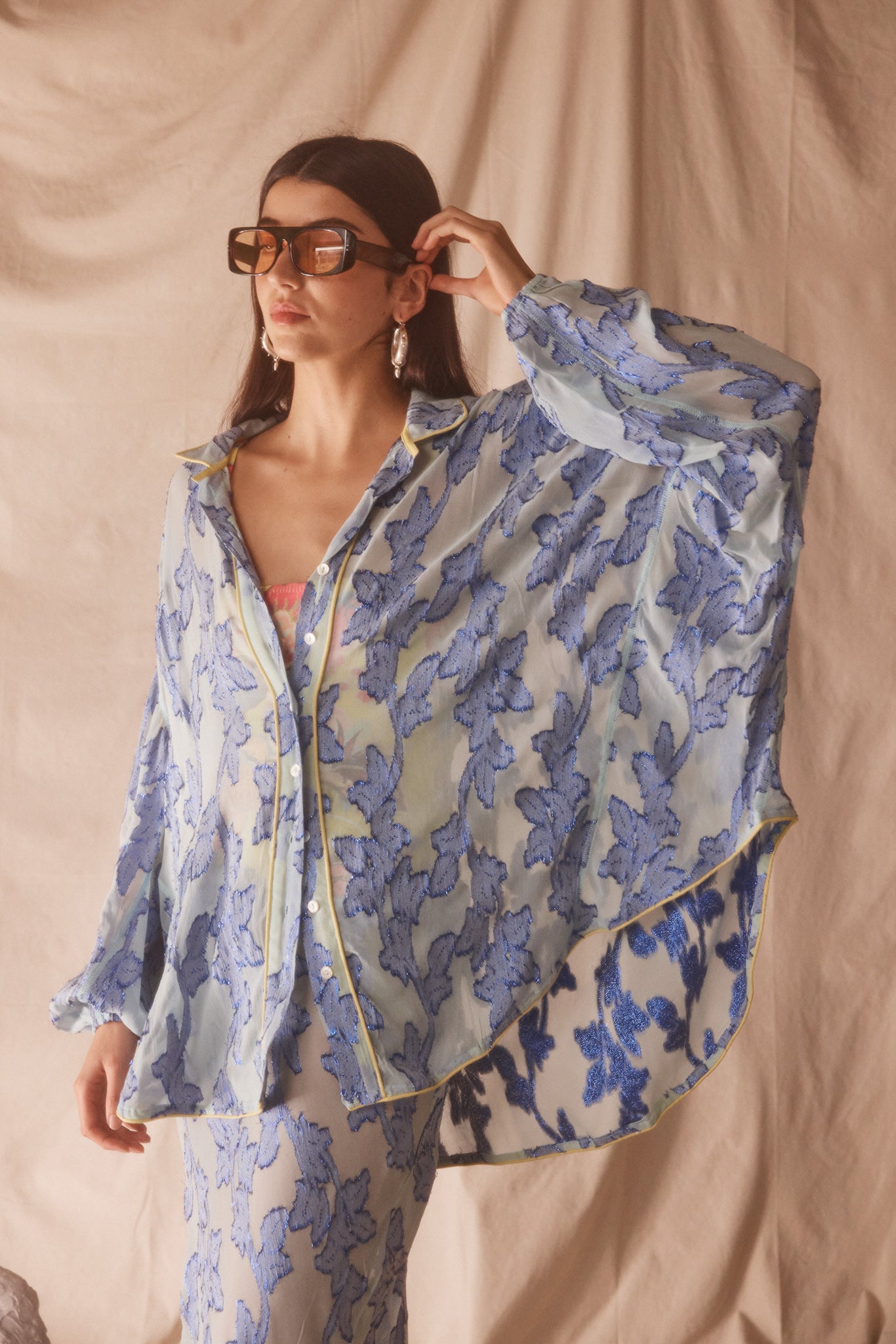 Woman wearing sheer cotton in electric blue botanical embroidery with contrast piping, curved hem, and oversized bohemian silhouette.