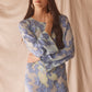 Woman wearing semi-sheer blue maxi with gold lurex florals, flared sleeves, and contrast piping. 
