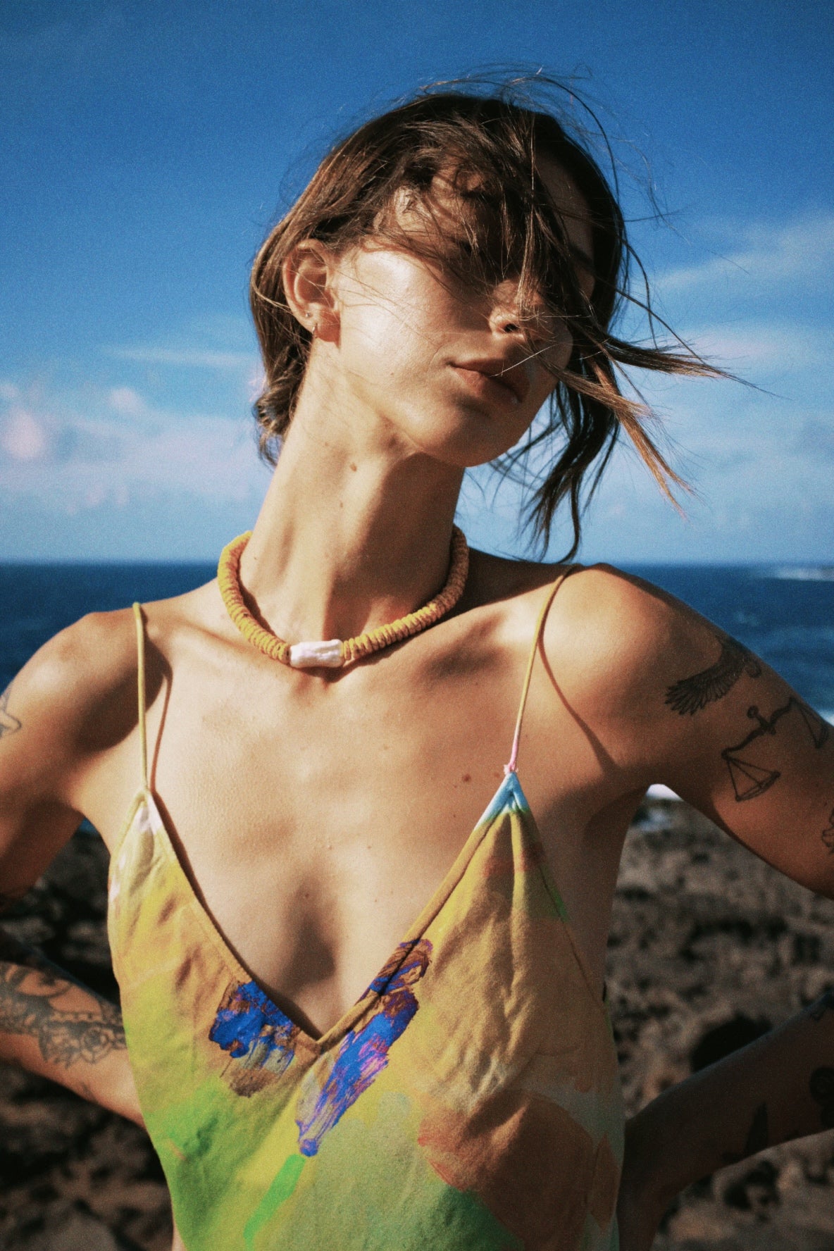 Woman in a colorful dress with a blue sky and ocean background