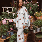 Model wearing Kinga Csilla Aquarius Chalm Shirt in celestial linen with matching Aquarius Column Skirt, styled among fresh flowers outside a Paris florist