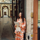 Model wearing Kinga Csilla Farfalla Chalm Shirt and Farfalla Jessi Pant in orange butterfly and cloud print. Women’s oversized button-up shirt with contrast piping styled with wide-leg pants matching set, relaxed streetwear co-ord.