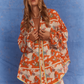 Close-up of model wearing Kinga Csilla Farfalla Chalm Shirt and Farfalla Jessi Pant in vibrant orange butterfly print co-ord set