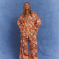 Model wearing Kinga Csilla Farfalla Chalm Shirt and Jessi Pant in bold orange butterfly print matching co-ord set.