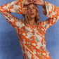 Close-up of the Kinga Csilla Farfalla Olive Dress in studio, highlighting the vivid orange butterfly and cloud print with flared sleeves and contrast trim.