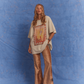 Model wears the Kinga Csilla Hibiscus Tee in studio against a blue backdrop, styled oversized with TWILIGHT VELVET FLARE PANT