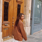 Close back view of model wearing Kinga Csilla Lino Roses Tee in brown, oversized long sleeve styled with Tottori Lace Ode Skirt, outdoor street scene