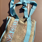 Kinga Csilla Rainy Lace KC Shoulder Bag flatlay on neutral background, featuring aqua blue straps, embroidered logo, and sage lace body detail.