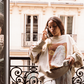 Kinga Csilla Shell OG Jumper in cream, oversized sweatshirt with shell and sun graphic, boho coastal-inspired sweater styled with lace pants on balcony, relaxed slouchy fit.