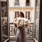 Model in Kinga Csilla Tottori Lace Ode Skirt, white cotton lace maxi skirt styled with Shell OG Jumper, standing on a Paris balcony editorial fashion look