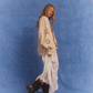 Side profile of model wearing Kinga Csilla Tottori Lace Ode Skirt, white lace maxi skirt styled with oversized beige Shell Og Jumper and black leather boots, studio photoshoot on blue backdrop