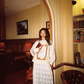 Model wearing Kinga Csilla Tottori Lace Ode Skirt, white lace maxi skirt styled with Shell OG Jumper, standing in vintage library-inspired interior look